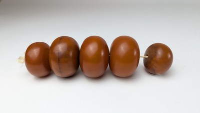 CINQ PERLES D'AMBRE montées en collier.